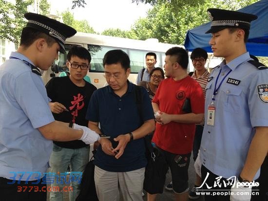 7月12日,北京市2013年高招录取现场,警察正在认真验证进入现场人员的身份。(记者林露 摄)